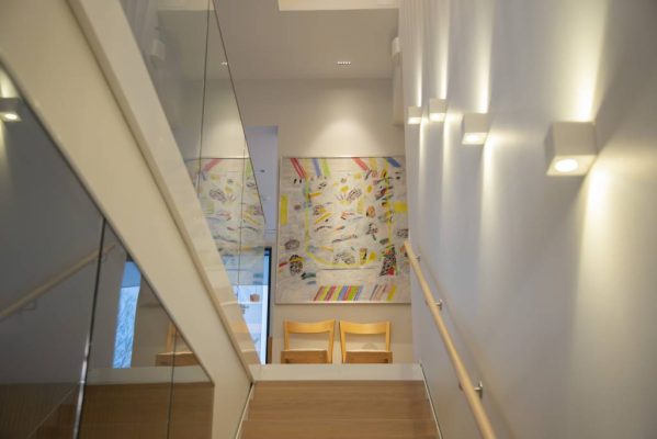 Nach oben und unten beleuchtete Wandleuchten XL Cubic, CCT als Treppenhausbeleuchtung, LINJA5 als Tischleuchte. © LedStore