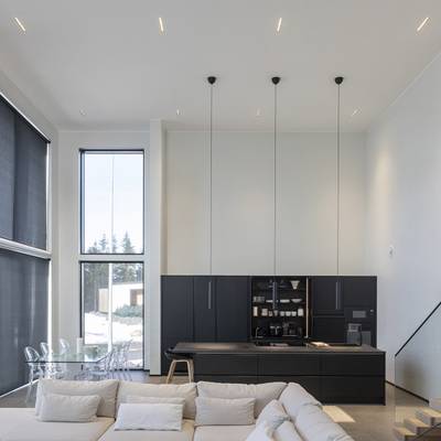 Moderne Küchenbeleuchtung mit Pendelleuchten, natürlichem Licht aus großen Fenstern, Ambient- und Akzent-LEDs.