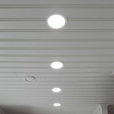 Vier LED-Deckeneinbauleuchten beleuchten einen weiß getäfelten Raum und präsentieren stilvolle moderne Beleuchtungslösungen.