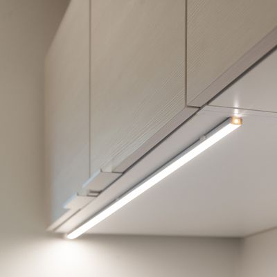 LED-Unterbauleuchten unter modernen Holzschränken beleuchten die Lichtwand und verbessern die Atmosphäre und Sichtbarkeit in der Küche.