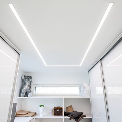 Ein minimalistisches Zimmer mit LED-Deckenleuchten, moderner Einrichtung mit Regalen, Schaufensterpuppen und Schiebetürenschränken mit Milchglasscheiben.