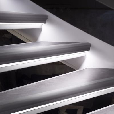 Detailaufnahme einer schwebenden Treppe mit stilvoller LED-Beleuchtung, Akzentbeleuchtung und einer weißen Wand.