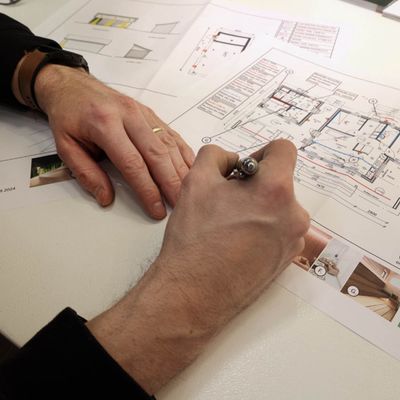 Lichttechnische Analyse von architektonischen Grundrissen mit Bleistift auf einem Schreibtisch im Zusammenhang mit der Innenbeleuchtung.