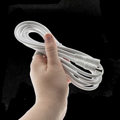 Handgedrehtes weißes Netzkabel mit Steckern, ideal für LED-Beleuchtungslösungen mit schwarzem Hintergrund.