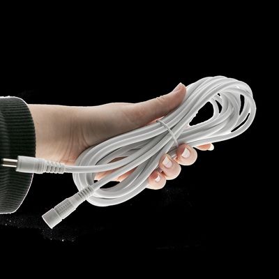 Nahaufnahme einer Hand, die ein verdrilltes weißes LED-Lichtkabel mit Steckern vor einem schwarzen Hintergrund hält, der moderne Beleuchtungslösungen hervorhebt.