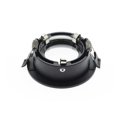 Schwarze Einbauleuchte mit Federklemmen aus Metall und einer runden Öffnung in der Mitte mit weißem Sockel. Ideal für moderne LED-Beleuchtungslösungen.