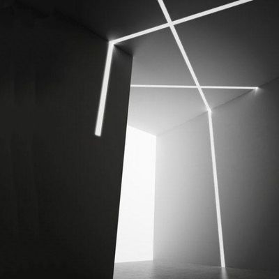 Ein dunkler, minimalistischer Raum, der durch sich kreuzende weiße LED-Linien an Wänden und Decke beleuchtet wird, die ein abstraktes geometrisches Lichtmuster bilden.