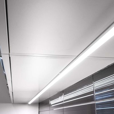 Modernes Interieur mit linearer LED-Deckenleuchte, die reflektierende graue Wandpaneele mit horizontalen Linien beleuchtet. Stilvolles und zeitgenössisches Beleuchtungsdesign.