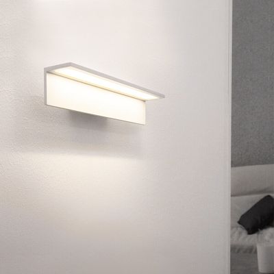 Eine moderne, minimalistische weiße Wandleuchte spendet sanftes Licht in zeitgenössischen Innenräumen.