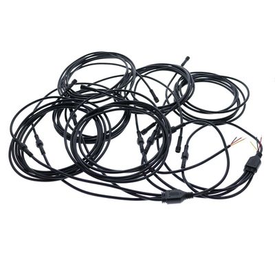 Schwarze LED-Glasfaserkabel mit Steckern und sichtbaren Drähten, gewickelt und verwickelt auf einem weißen Hintergrund.