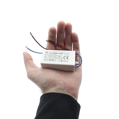 Kleine rechteckige LED-Stromversorgung mit sichtbaren Drähten, weißer Hintergrund. Komponente einer energieeffizienten Beleuchtungslösung.