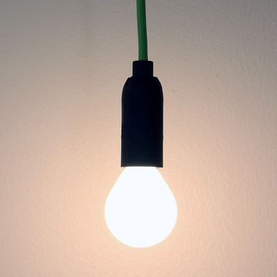 Hängende LED-Lampe mit grünem Draht auf einem flachen Hintergrund, präsentiert energieeffiziente Beleuchtung. Perfekt für das moderne Zuhause und umweltfreundliche Beleuchtungslösungen.