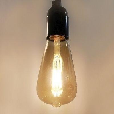 Vintage-LED-Lampe mit schwarzem Sockel, die auf einem schlichten Hintergrund hängt - perfekt für Retro- und energieeffiziente Beleuchtungslösungen.