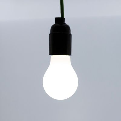 Eine LED-Lampe mit grünem Glühfaden, die vor einem grauen Hintergrund leuchtet und energieeffiziente Beleuchtungslösungen hervorhebt.