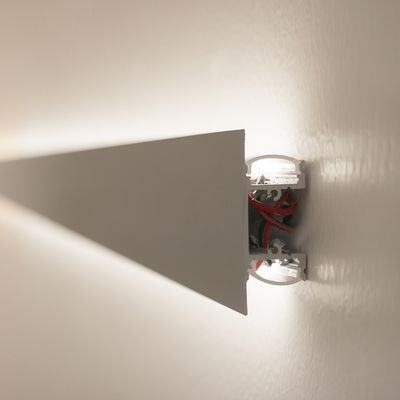 Minimalistische Wandleuchte mit dreieckigem Balken, der rote Drähte und Komponenten zeigt. Ideal für moderne Innenräume und energieeffiziente LED-Beleuchtung.
