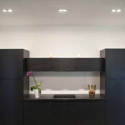 Minimalistisches schwarzes Badezimmer mit LED-Beleuchtung, kleinem Waschbecken, Orchidee mit weißem Topf auf der linken Seite, Kerzenständer aus Glas auf der rechten Seite für Eleganz und Stil.