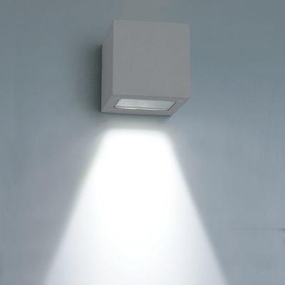 Die würfelförmige LED-Wandleuchte wirft einen hellen, nach unten gerichteten Lichtstrahl auf eine zartblaue Wand und akzentuiert moderne Innenräume mit energieeffizienter Beleuchtung.
