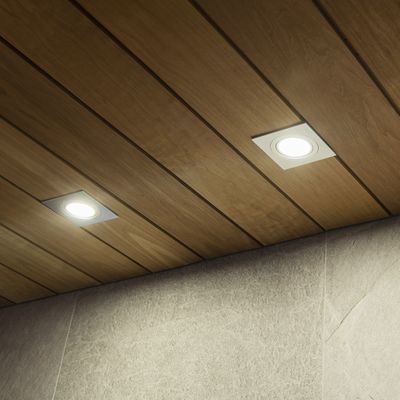 Alternativer Text: 'Holzdecke mit LED-Einbauleuchten, die eine strukturierte graue Wand in einem modernen Beleuchtungsgeschäft beleuchten