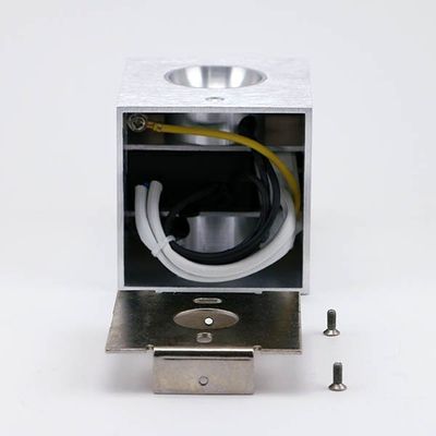 Quadratisches LED-Leuchtengehäuse aus Metall mit Drähten, Halterung und zwei Schrauben auf einem weißen Sockel - ideal für eine effiziente LED-Beleuchtungsinstallation.