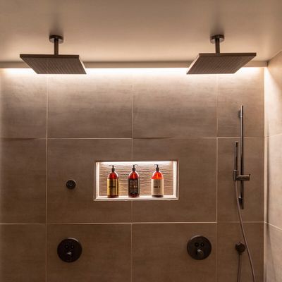 Alternativer Text: 'Zeitgenössische Dusche mit zwei quadratischen LED-Leuchten, drei Flaschen und Handbrause mit beige gefliester Wand.