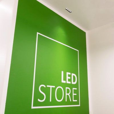Alternativer Text: 'Grüne Wand mit 'LED STORE', weißer quadratischer Umriss, fette Buchstaben, Deckenbeleuchtung