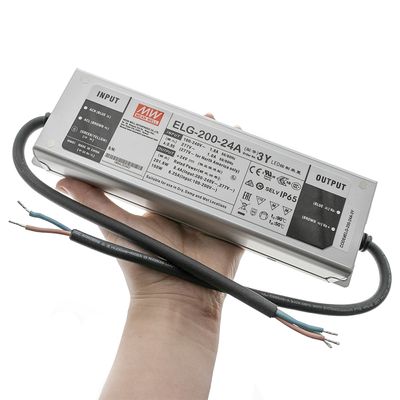 Nahaufnahme des handgehaltenen Mean Well ELG-200-24A LED-Controllers mit sichtbaren Eingangs- und Ausgangskabeln, ideal für energieeffiziente LED-Beleuchtungslösungen.