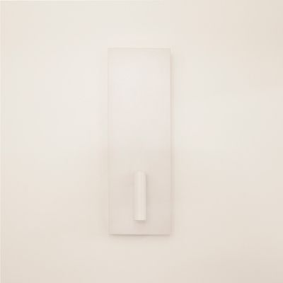 Minimalistische weiße Wandskulptur mit rechteckigem Sockel und zentralem zylindrischem Vorsprung, beleuchtet durch LED-Beleuchtung, um die Attraktivität des Designs zu erhöhen.