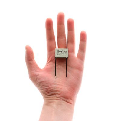 Nahaufnahme einer Hand mit einer zweipoligen LED-Diodenkomponente, ideal für energieeffiziente Beleuchtungslösungen, auf weißem Hintergrund.
