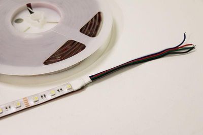 LED-Leuchtband mit roten, grünen und schwarzen Drähten auf weißer Oberfläche für die Heimdekoration, Schrankbeleuchtung, energieeffiziente Lösungen.