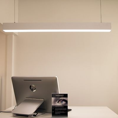 Minimalistisches Büro mit Computermonitor, Präsentationsständer und stilvoller rechteckiger LED-Deckenleuchte, die eine moderne Arbeitsplatzatmosphäre schafft.
