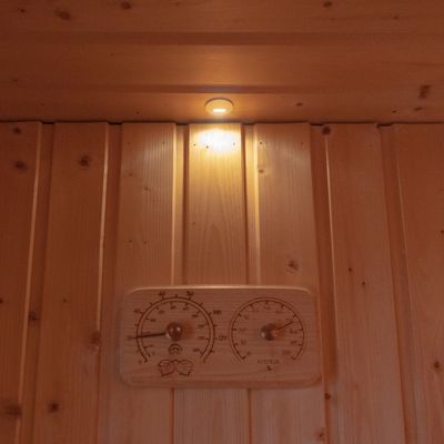 Holzgetäfelter Wandaufsteller mit LED-beleuchtetem Lämpchen und Holzkachel mit eingebautem Thermometer und Hygrometer für eine moderne Wohnatmosphäre.
