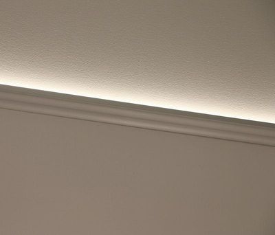 Eine moderne weiße Sockelleiste mit einem subtilen LED-Lichteffekt, der die Wand beleuchtet und ein klares und modernes Design unterstreicht.