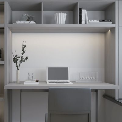 Minimalistischer Arbeitsbereich mit Laptop, Wasserglas, Buch und Pflanze auf dem Tisch; obere Regale mit Büchern und Dekorationsartikeln. LED-Beleuchtung erhellt den Bereich.