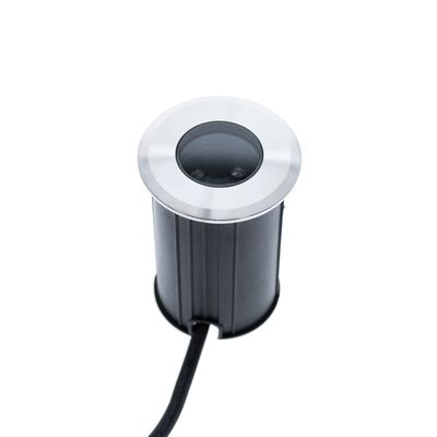 Alternativtext: "Zylindrische LED-Leuchte aus Metall mit schwarzem Hintergrund und sichtbarer Linse, verbunden mit einem Kabel - eine moderne Beleuchtungslösung.