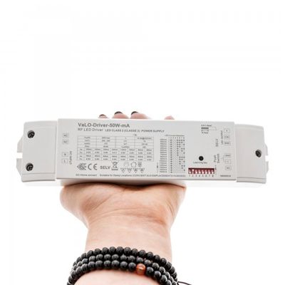 Nahaufnahme einer Hand, die ein rechteckiges LED-Treiber-Netzteil hält, das die Spezifikationen und mehrere Anschlüsse von LED-Beleuchtungslösungen zeigt.