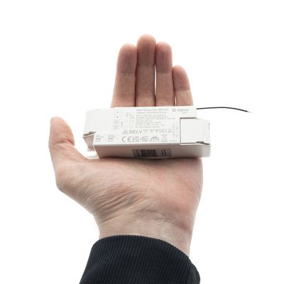 Eine Person hält eine LED-Lichtsteuerung, die Größe und Funktion anzeigt und moderne Beleuchtungstechnik in einem Geschäft präsentiert.