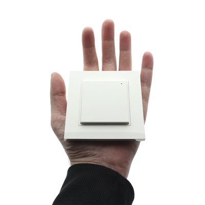 Handlicher, quadratischer, weißer, moderner Lichtschalter vor weißem Hintergrund, der die fortschrittliche LED-Beleuchtungssteuerung symbolisiert. Ideal für zeitgenössisches Wohndesign.