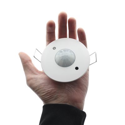 Runder, weißer Handsensor mit zentralem Drehknopf und zwei Metallclips; ideal für die energieeffiziente Automatisierung von LED-Beleuchtung.