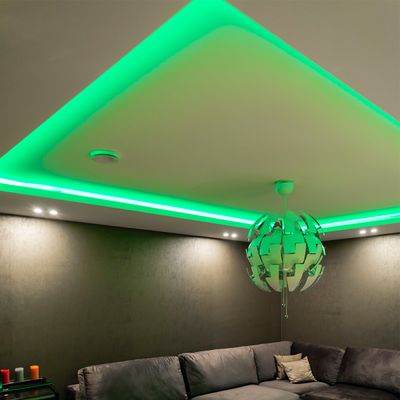 Modernes Wohnzimmer mit LED-Deckenleuchten, grauem Sofa, Pendelleuchte und Wandbeleuchtung