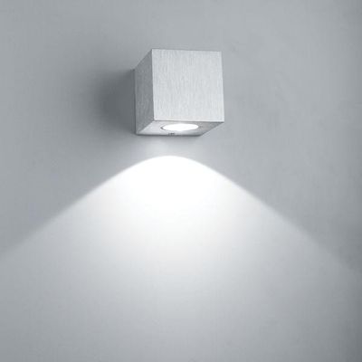 Die würfelförmige Wandleuchte beleuchtet symmetrische Strahlen auf einer grauen Oberfläche und akzentuiert moderne Interieurs mit stilvoller LED-Beleuchtung.