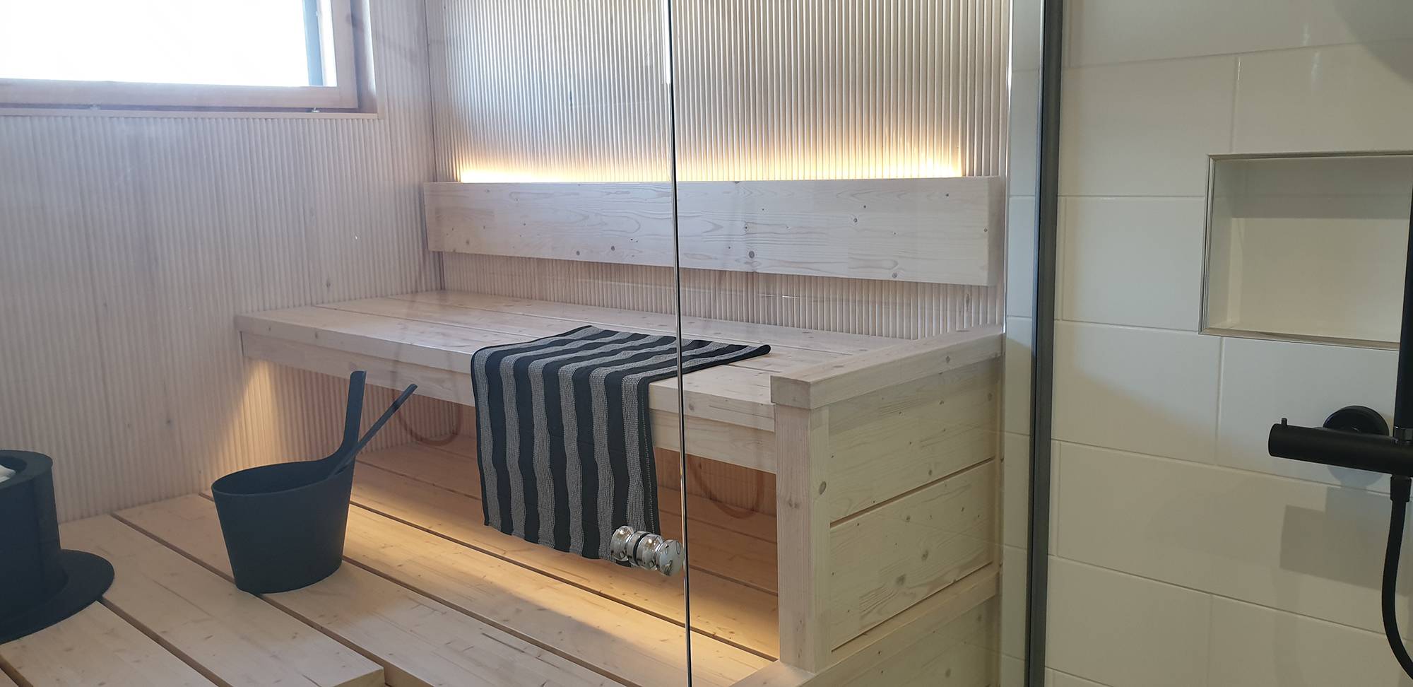LED-Leiste an der Rückseite der Saunarückenlehne strahlt stimmungsvolles Licht nach oben und unten unter die Decke. Ledstore.fi