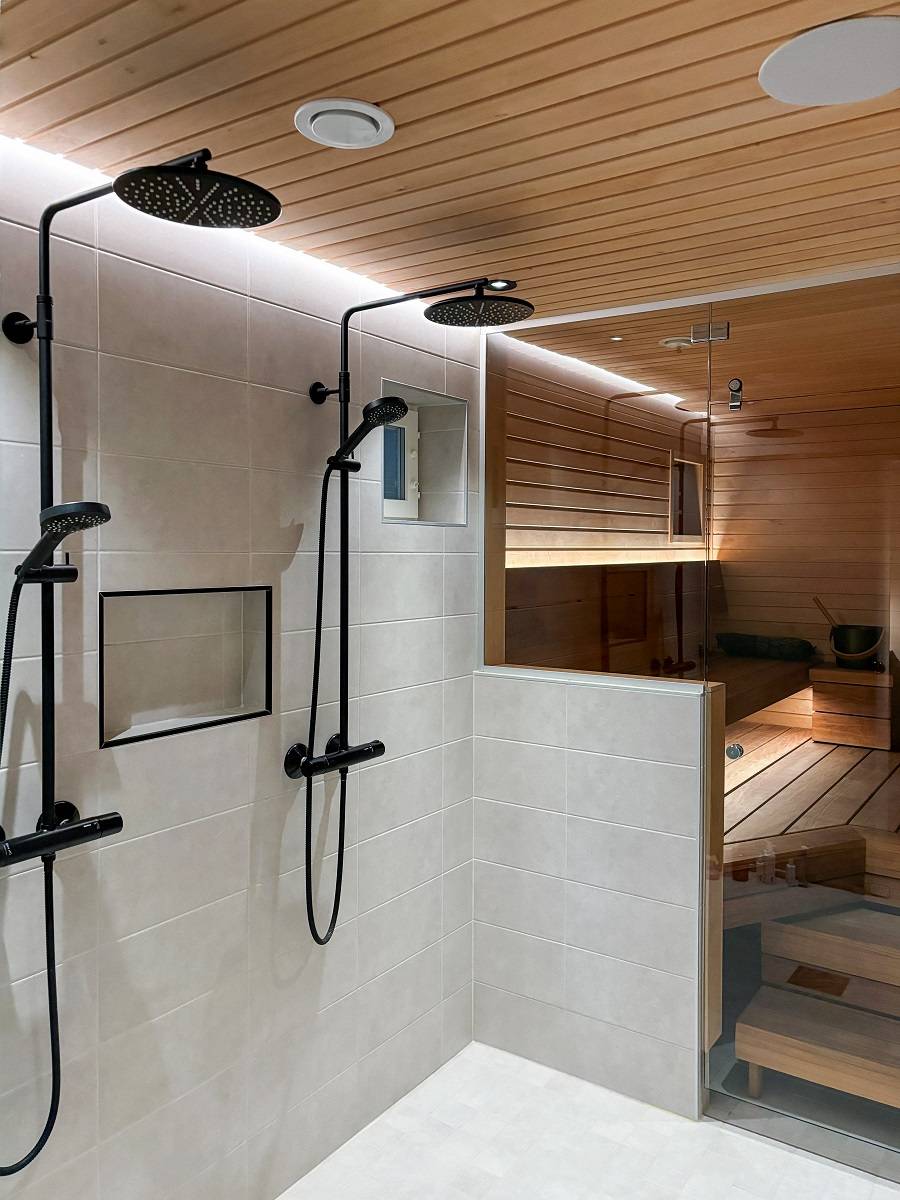Hinter den Duschen leuchtet ein LED-Lichtband in einer Nut in der Deckenlinie indirekt an der Wand entlang bis zum Boden. Das Licht ist sowohl effizient als auch augenfreundlich. © LedStore.fi