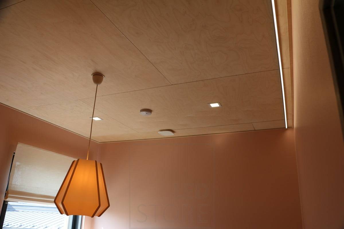 Wohnungsmesse 2019: Kleine Flächenleuchten auf einem Sperrholzdach. Led-Streifen zur Beleuchtung der Wand für indirektes Licht. Ledstore.fi