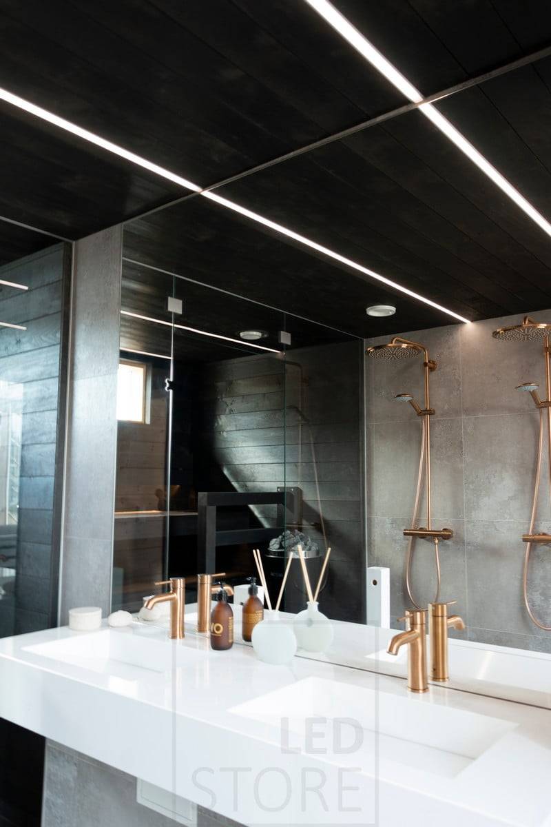 Wohnmesse 2020: LED-Leisten beleuchten das Badezimmer in schmalen Einbauprofilen in der schwarzen Decke des Waschraums. Die Beleuchtung erzeugt schöne Lichtlinien an der Decke. Ledstore.fi