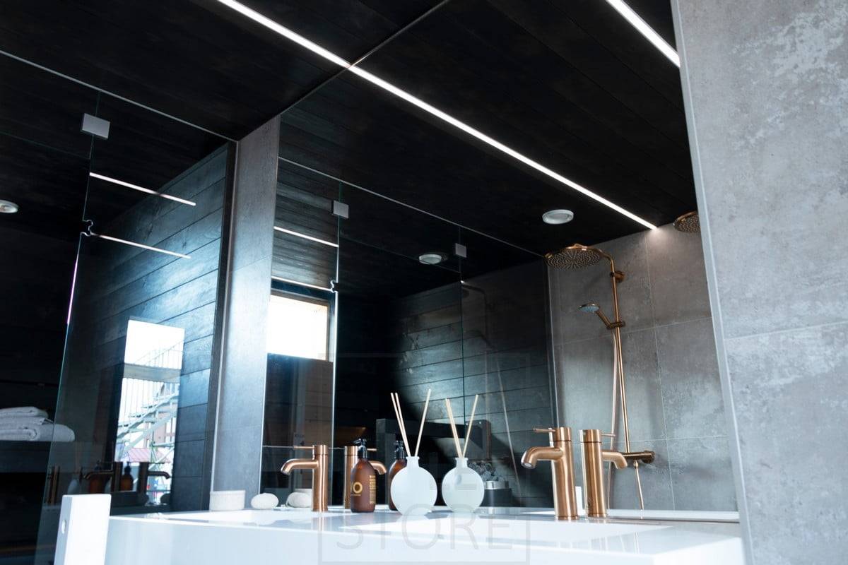 Wohnmesse 2020: LED-Streifen zur Beleuchtung des Badezimmers in schmalen Einbauprofilen an der schwarzen Decke des Waschraums. Ledstore.fi