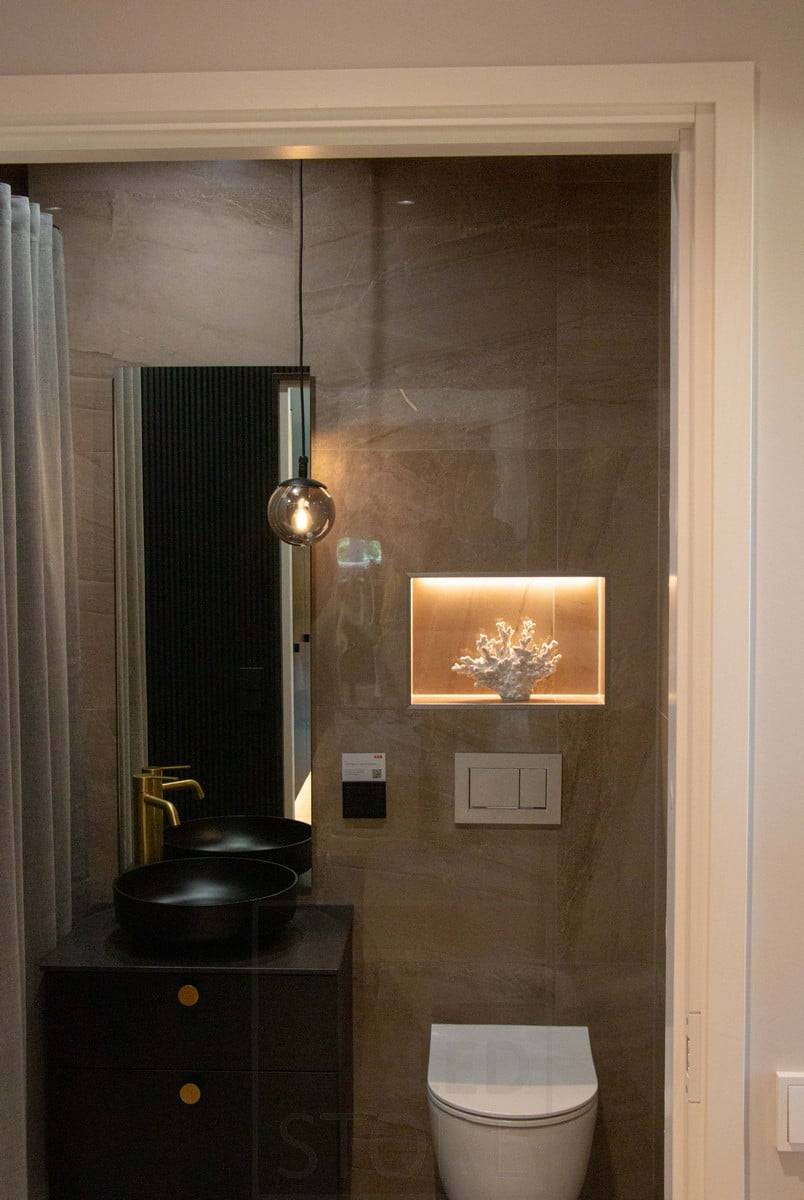 Wohnmesse 2022: Ein in die Wand eingelassenes Regal im Toilettenraum ist mit einem LED-Band versehen, das das Detail hervorhebt. Eine Pendelleuchte als stimmungsvolles Dekorationselement. Ledstore.fi
