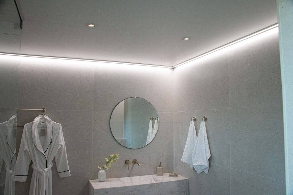 Gehäuse Fair 2022: Led-Leiste, die auf einer flachen Oberfläche an der Decke neben der Wand montiert ist und ein weiches, indirektes Licht für das Badezimmer liefert. Ledstore.fi