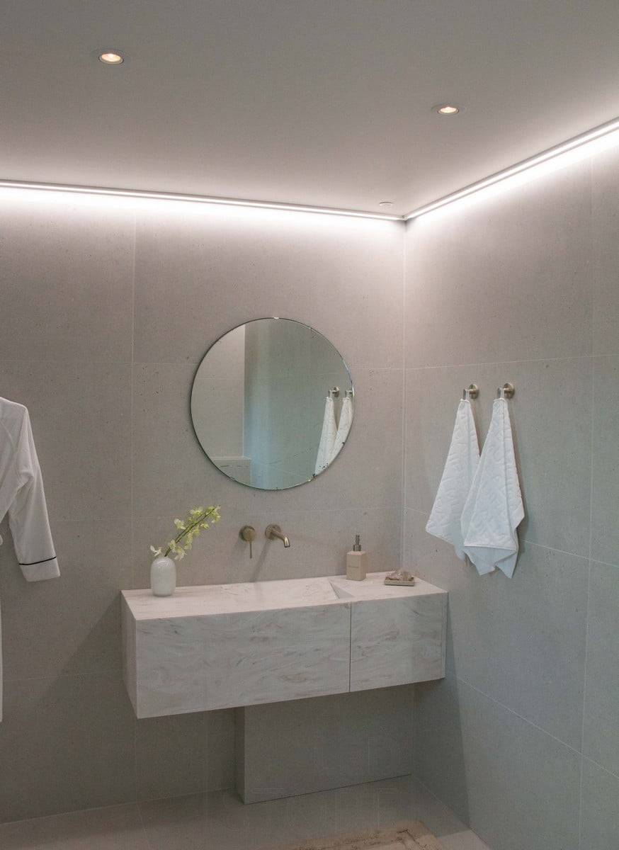 Housing Fair 2022: Led-Leiste, die auf einer flachen Oberfläche an der Decke neben der Wand montiert ist und das Badezimmer mit stimmungsvollem Licht beleuchtet. Ledstore.fi