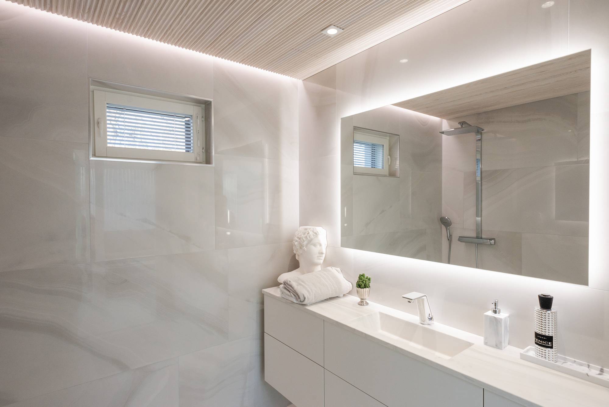 In einem Badezimmer mit Wellness-Badewanne wird ein großer, platzraubender Lichtspiegel mit Strahlern und einem wandhohen LED-Band kombiniert.