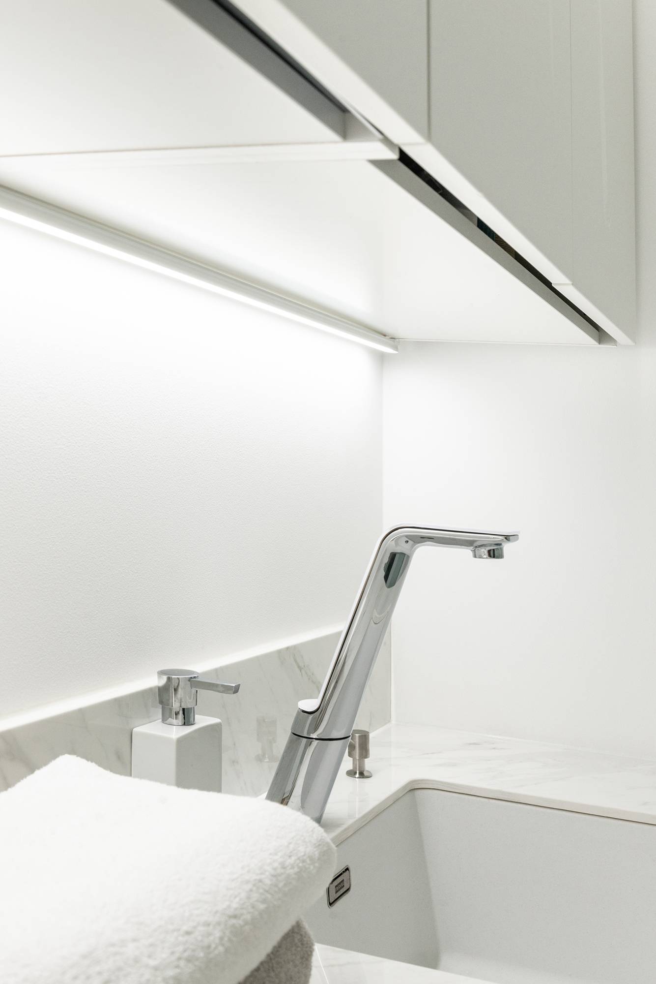 Im Hauswirtschaftsraum, in der Ecke des Schranks und der Wand, in einem hohen Oberflächenprofil, bringt eine LED-Leiste Licht auf die Ebene. Ledstore.fi